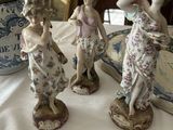 trois figurines posées sur une table, avec un vase en arrière-plan