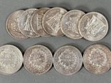 six different types of silver coins on a gray surface