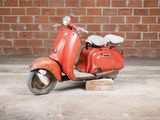 a small red scooter sitting on a wooden block
