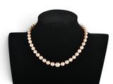 a white pearl necklace on a black mannequin