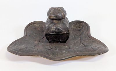 une petite statue représentant une personne assise sur une feuille