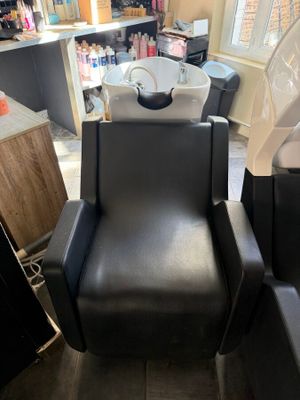 a black chair in the corner of a hair salon