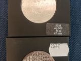 two different types of silver coins are on display in a box