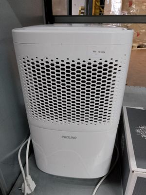 un purificateur d'air blanc posé par terre à côté d'une pile de cartons