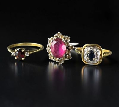three gold rings with diamonds and a ruby stone