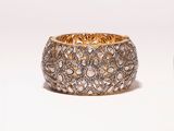 a close up of a gold and diamond bracelet on a white background