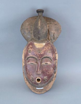 une image représentant un masque en bois orné d'un visage et d'un chapeau