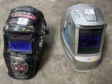 two welding helmets sitting on the ground next to each other