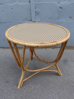 an image of a wicker table on a sidewalk with a blue wall in the background