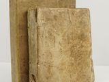 two old books sitting on top of each other on a white surface