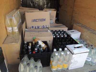 many bottles of water sitting on the floor next to boxes