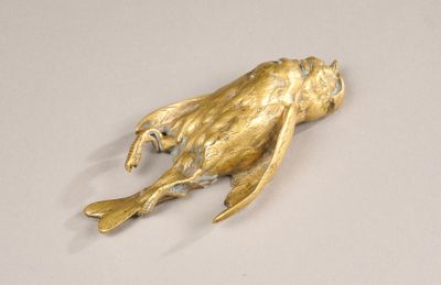 une statue en or représentant une grenouille posée sur un fond blanc