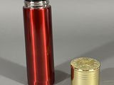 une bouteille rouge et dorée à côté d'une pièce d'or