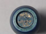 a close up of a blue bottle with a gold writing on it