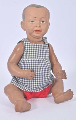 a baby doll sitting on the floor with a blue and white checkered dress