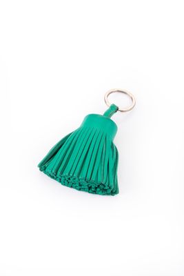 un porte-clés vert orné d'un pompon et muni d'un anneau métallique, sur fond blanc