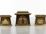 three wooden statues of people in a church with a glass case