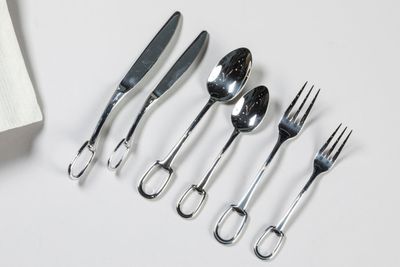 five forks, a spoon, and a knife on a white table