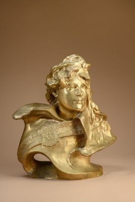 bronze bust of a young boy with long hair and a hat