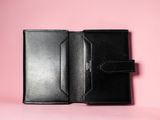 a black leather wallet with a card holder on a pink background