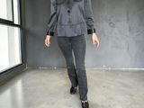 a woman standing in a room with a gray jacket and black pants