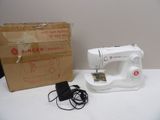 a white sewing machine sitting on a table next to a box