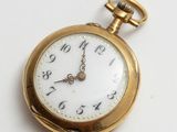 gros plan d'une montre de poche en or sur une surface blanche