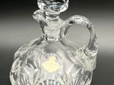 an image of a clear glass bottle with a handle on a black surface