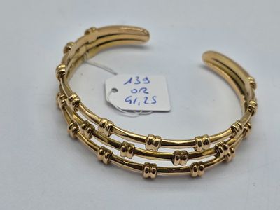 gros plan d'un bracelet en or sur une surface blanche