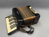 the accordion is sitting on a white surface with a black case