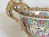 a large ornate bowl on a table with a mirror in the background