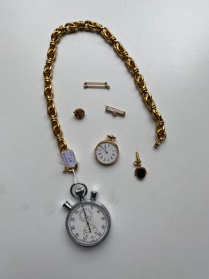 un gros plan sur une chaîne en or ornée d'une montre et d'autres objets