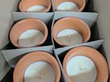 des bougies dans des pots en argile, dans une boîte en carton posée sur une table