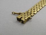 une image représentant un bracelet en or muni d'un fermoir, posé sur une surface blanche