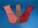 three different colored ties on a blue surface with one red and one black