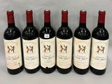 six bottles of wine are lined up in a row on a table