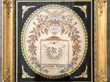 un tableau dans un cadre ouvragé représentant un blason sur lequel figure un blason