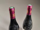 two bottles of wine sitting next to each other on a table