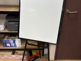 un tableau blanc posé sur un trépied dans une pièce