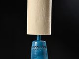 a blue table lamp with a beige shade on it