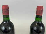 two bottles of red wine sitting next to each other on a table
