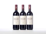 three bottles of red wine sitting on top of a white table