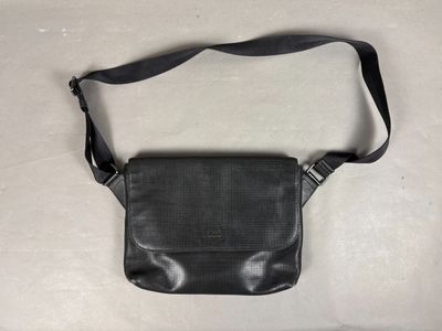 un sac à main en cuir noir muni d'une bandoulière noire sur un fond blanc