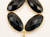 a close up of a necklace with black stones on a white background