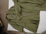 a green jacket laying on the floor next to a pair of shoes