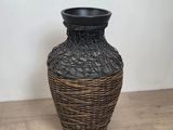 a wicker vase sitting on a wooden floor