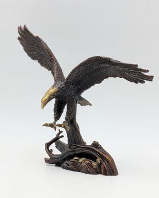 statue of an eagle perched on a tree branch with its wings spread
