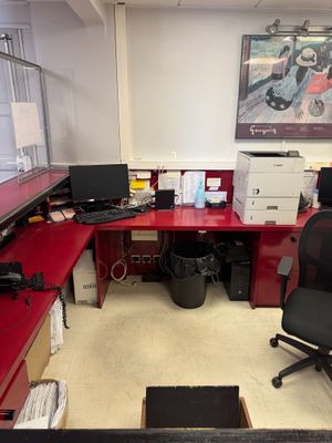 a red desk with a black chair and a computer on it