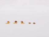 three pairs of gold stud earrings sitting on top of a white surface