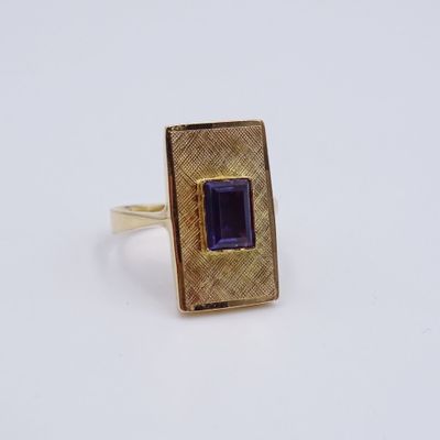 Gros plan sur une bague en or ornée d'une pierre violette.